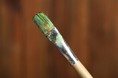 Photo of One dirty paintbrush on wooden background, closeup