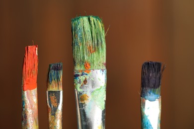 Photo of Many dirty paintbrushes on wooden background, closeup