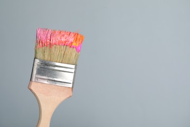 Photo of Brush with paint on light grey background, closeup. Space for text