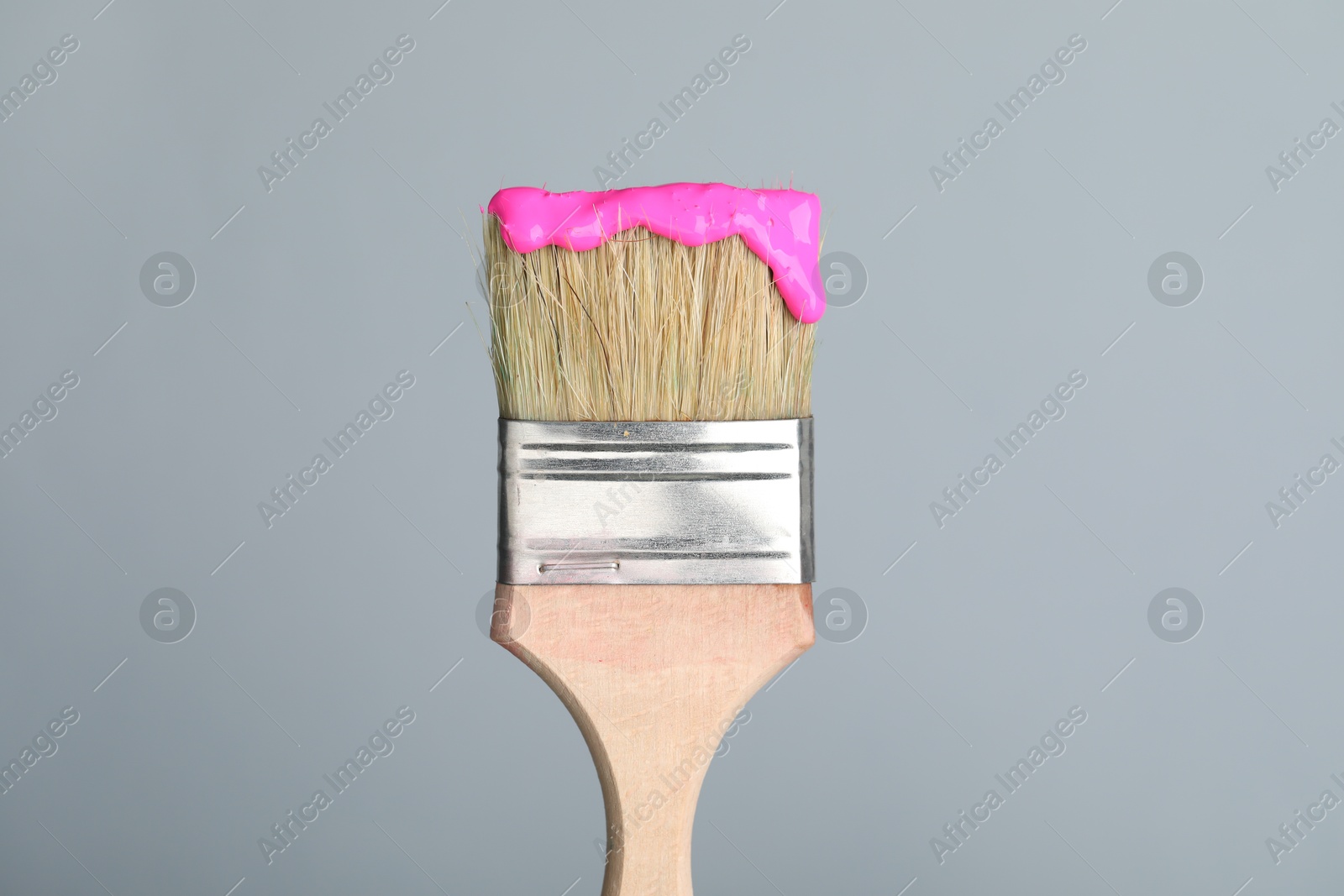 Brush with pink paint on light grey background, closeup Photo of Brush with pink paint on light grey background, closeup