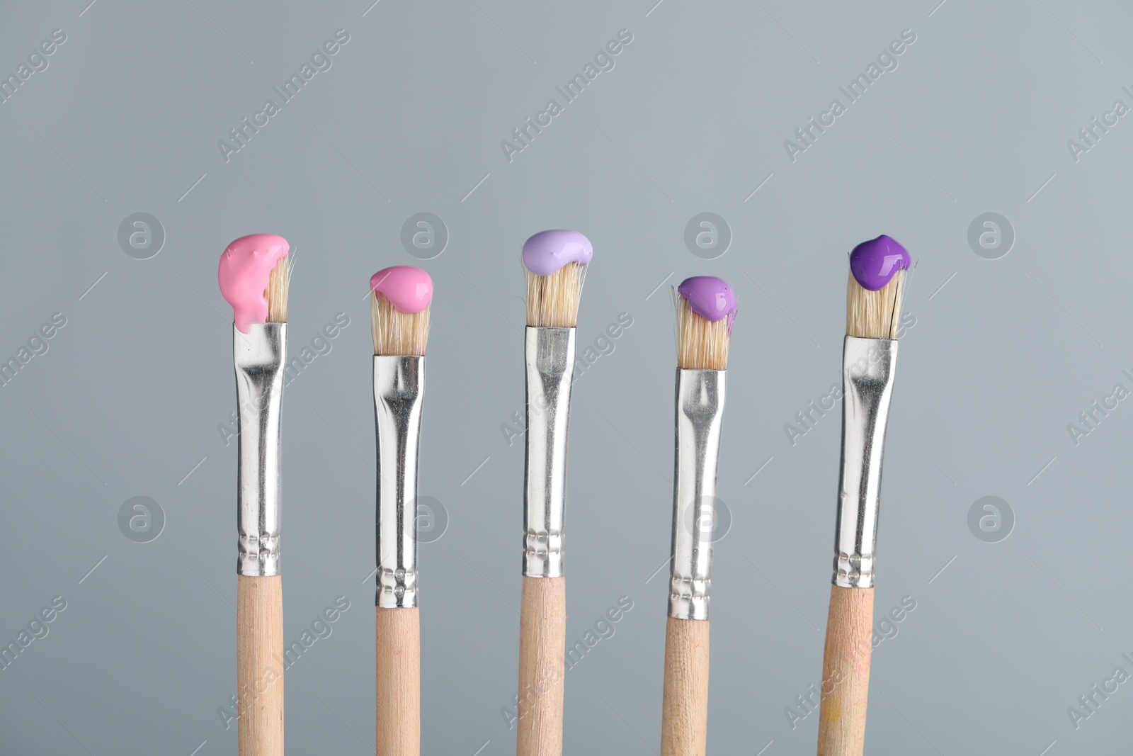 Many brushes with color paints on light grey background, closeup Photo of Many brushes with color paints on light grey background, closeup