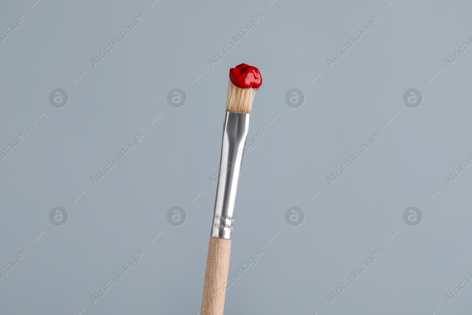 Brush with red paint on light grey background, closeup Photo of Brush with red paint on light grey background, closeup