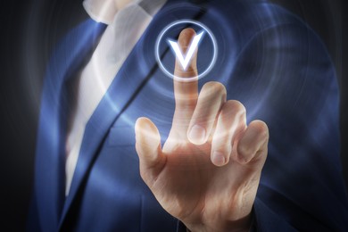 Image of Approved. Businessman touching check mark on virtual screen against black background, closeup