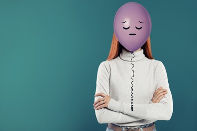 Image of Balloon with sad face in front of woman's head on blue background. Space for text