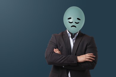 Image of Balloon with sad face instead of man's head on blue grey background. Space for text