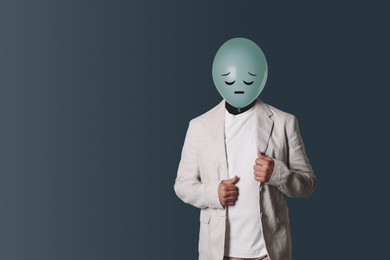 Image of Balloon with sad face instead of man's head on dark grey background. Space for text