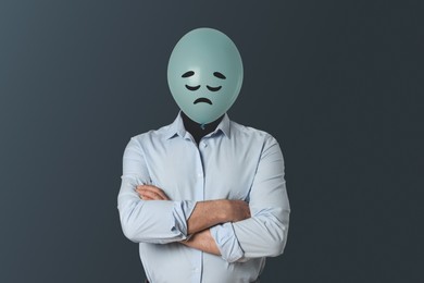 Image of Balloon with sad face instead of man's head on dark grey background