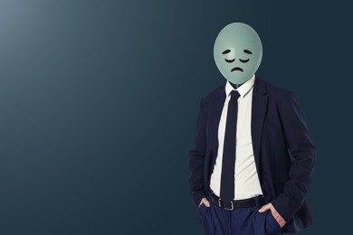 Image of Balloon with sad face instead of man's head on blue grey background. Space for text