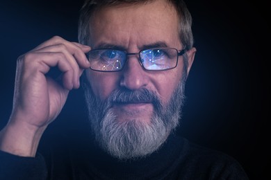 Image of Stock exchange. Trader analyzing data on black background, closeup. Graphs reflecting in his eyeglasses