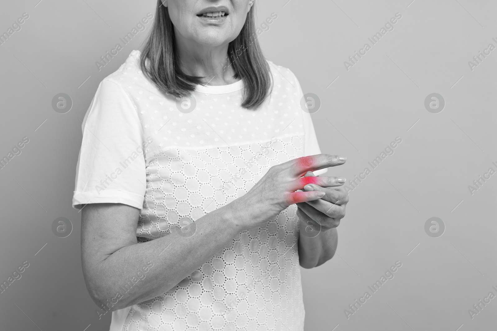 Arthritis. Woman suffering from pain in fingers, closeup. Black and white toning with red color accent Image of Arthritis. Woman suffering from pain in fingers, closeup. Black and white toning with red color accent