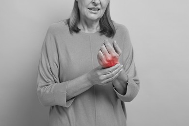 Image of Arthritis. Woman suffering from pain in hand, closeup. Black and white toning with red color accent