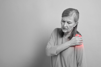 Image of Arthritis. Senior woman suffering from pain in shoulder, space for text. Black and white toning with red color accent