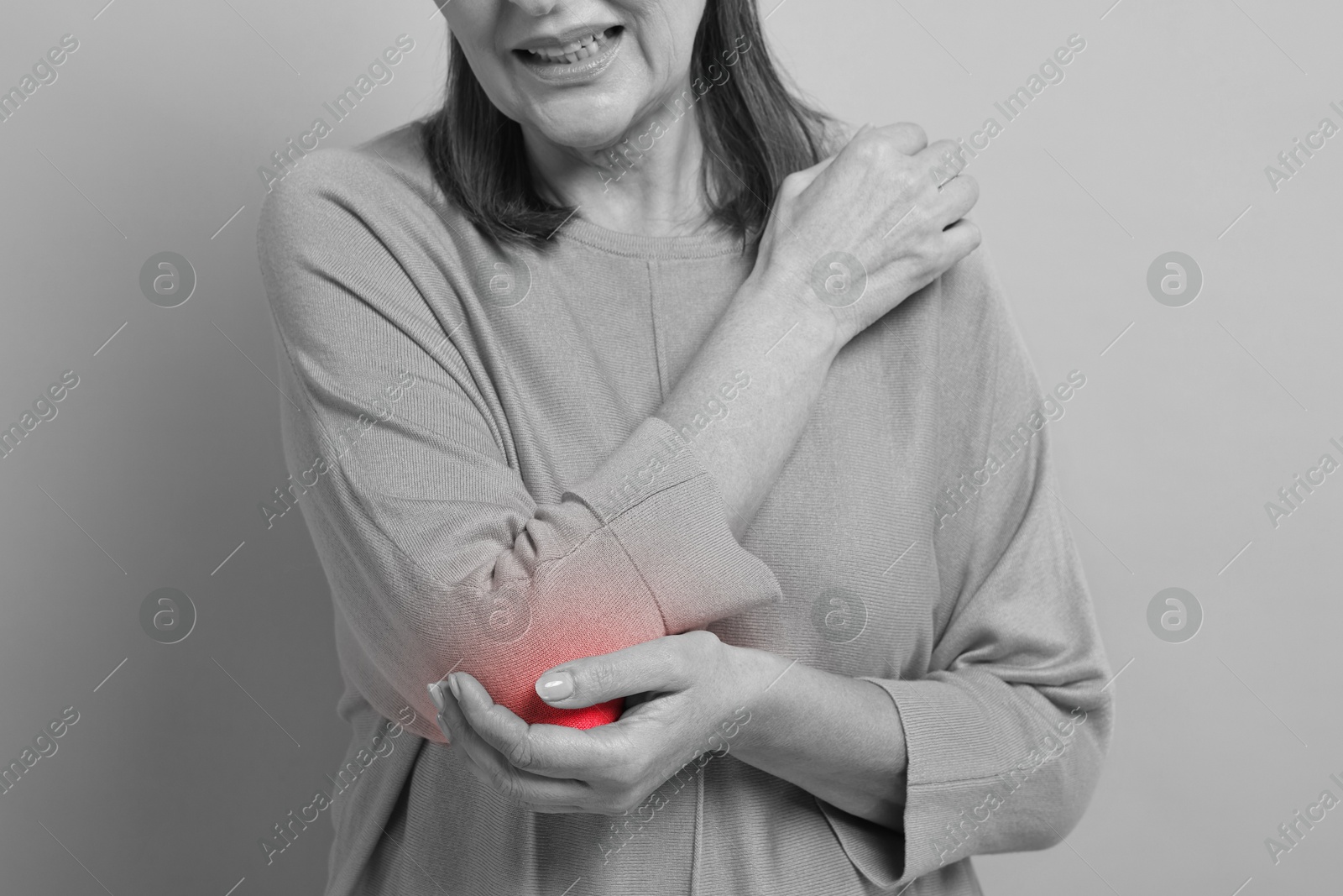 Arthritis. Senior woman suffering from pain in elbow, closeup. Black and white toning with red color accent Image of Arthritis. Senior woman suffering from pain in elbow, closeup. Black and white toning with red color accent