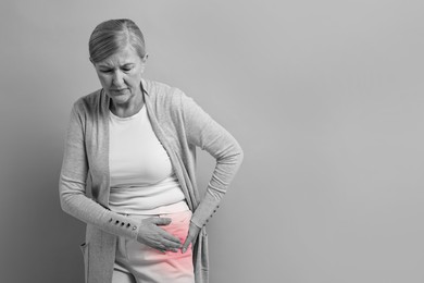 Image of Arthritis. Senior woman suffering from hip joint pain, space for text. Black and white toning with red color accent