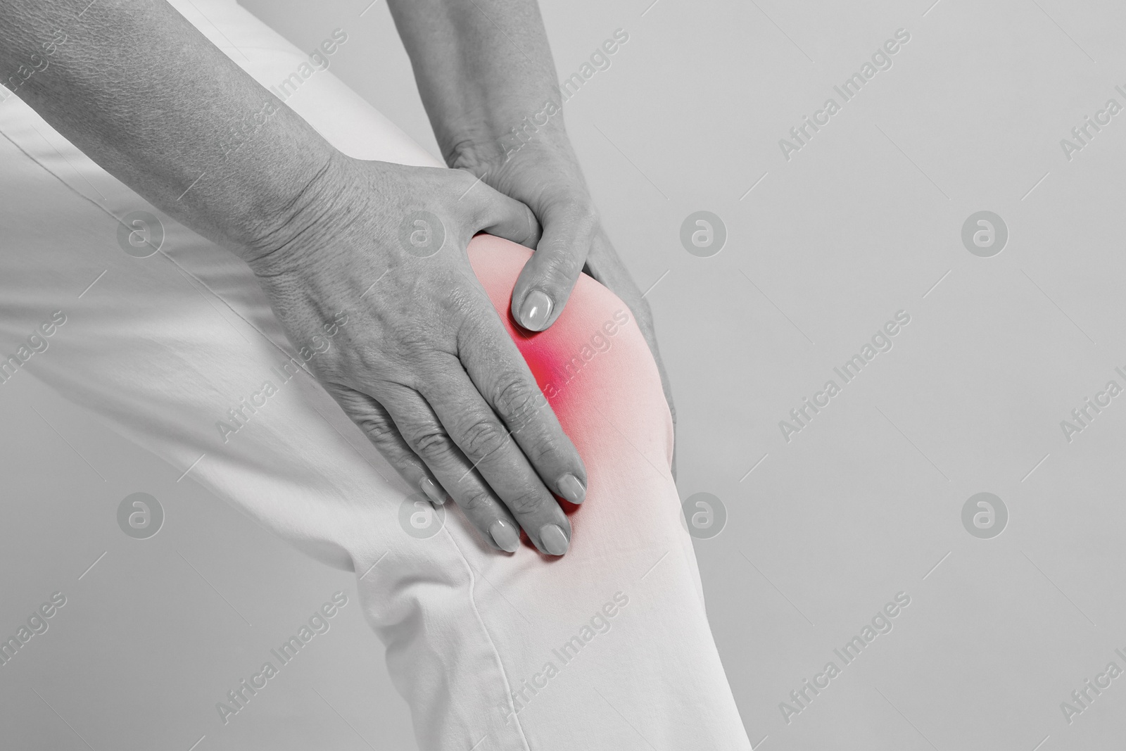 Arthritis. Woman suffering from pain in knee, closeup. Black and white toning with red color accent Image of Arthritis. Woman suffering from pain in knee, closeup. Black and white toning with red color accent