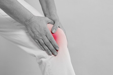 Image of Arthritis. Woman suffering from pain in knee, closeup. Black and white toning with red color accent
