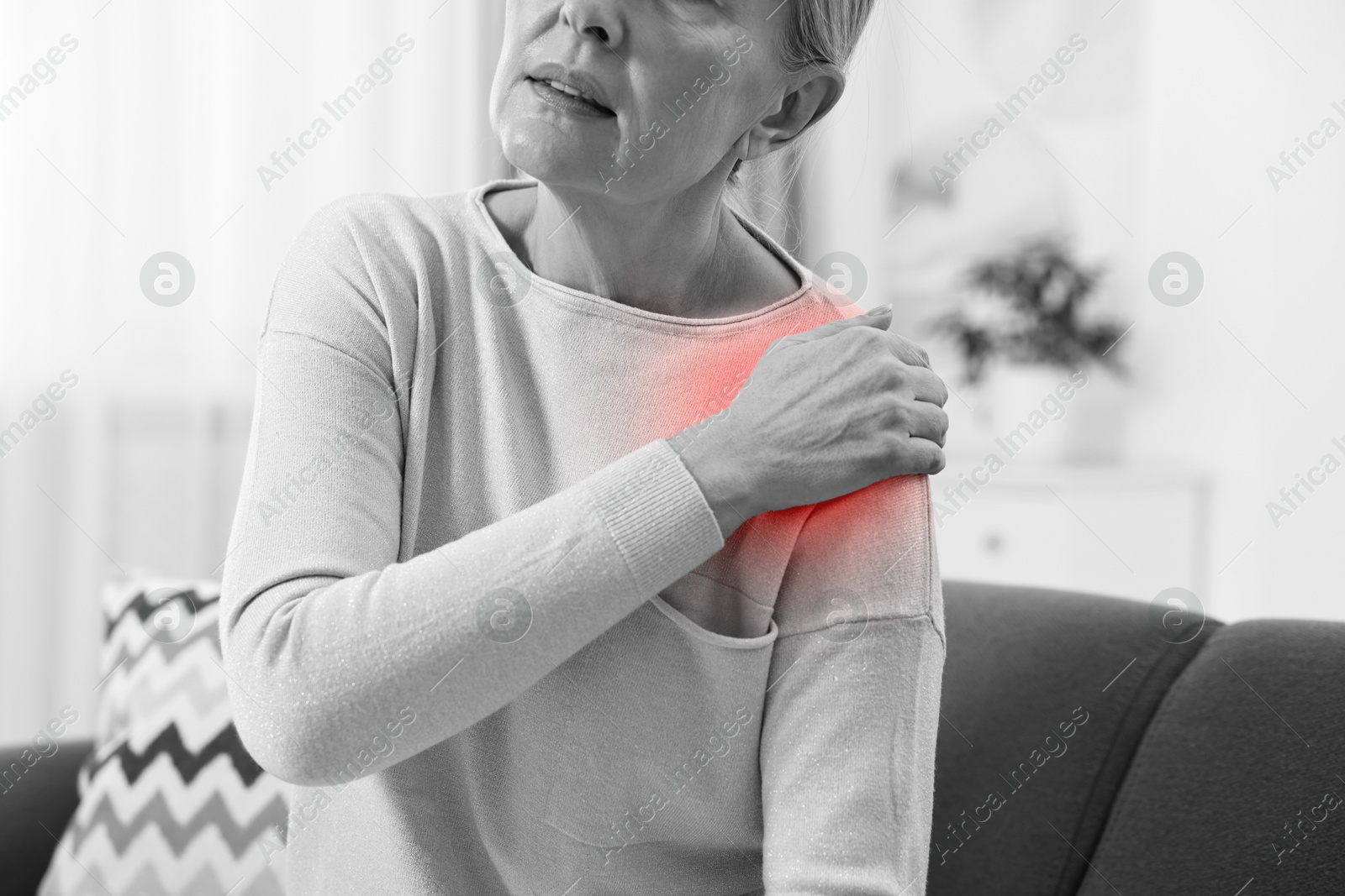 Arthritis. Senior woman suffering from pain in shoulder at home, closeup. Black and white toning with red color accent Image of Arthritis. Senior woman suffering from pain in shoulder at home, closeup. Black and white toning with red color accent
