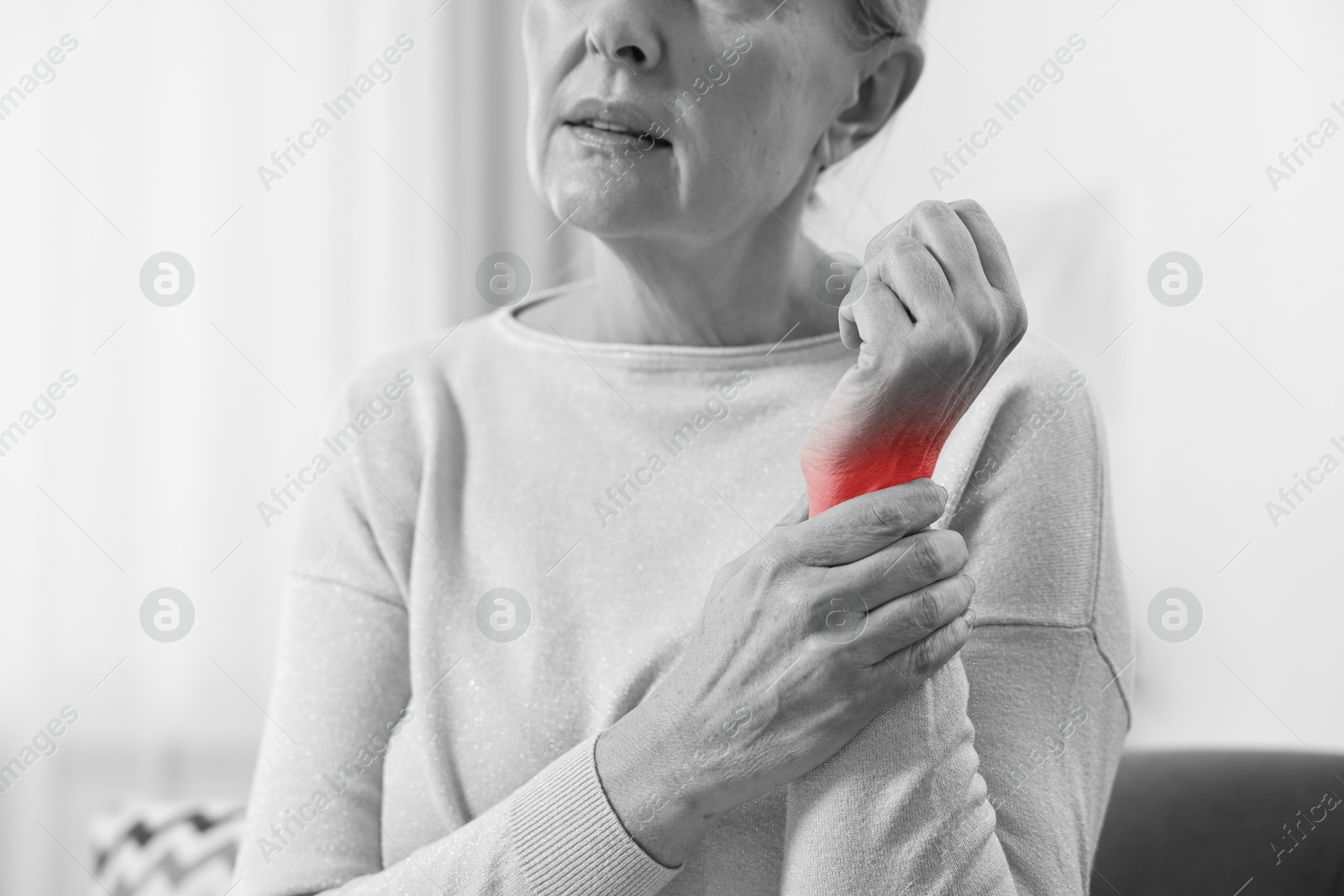 Arthritis. Senior woman suffering from wrist pain indoors, closeup. Black and white toning with red color accent Image of Arthritis. Senior woman suffering from wrist pain indoors, closeup. Black and white toning with red color accent