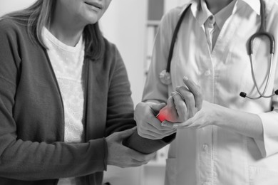 Image of Arthritis. Doctor examining patient's wrist in hospital, closeup. Black and white toning with red color accent