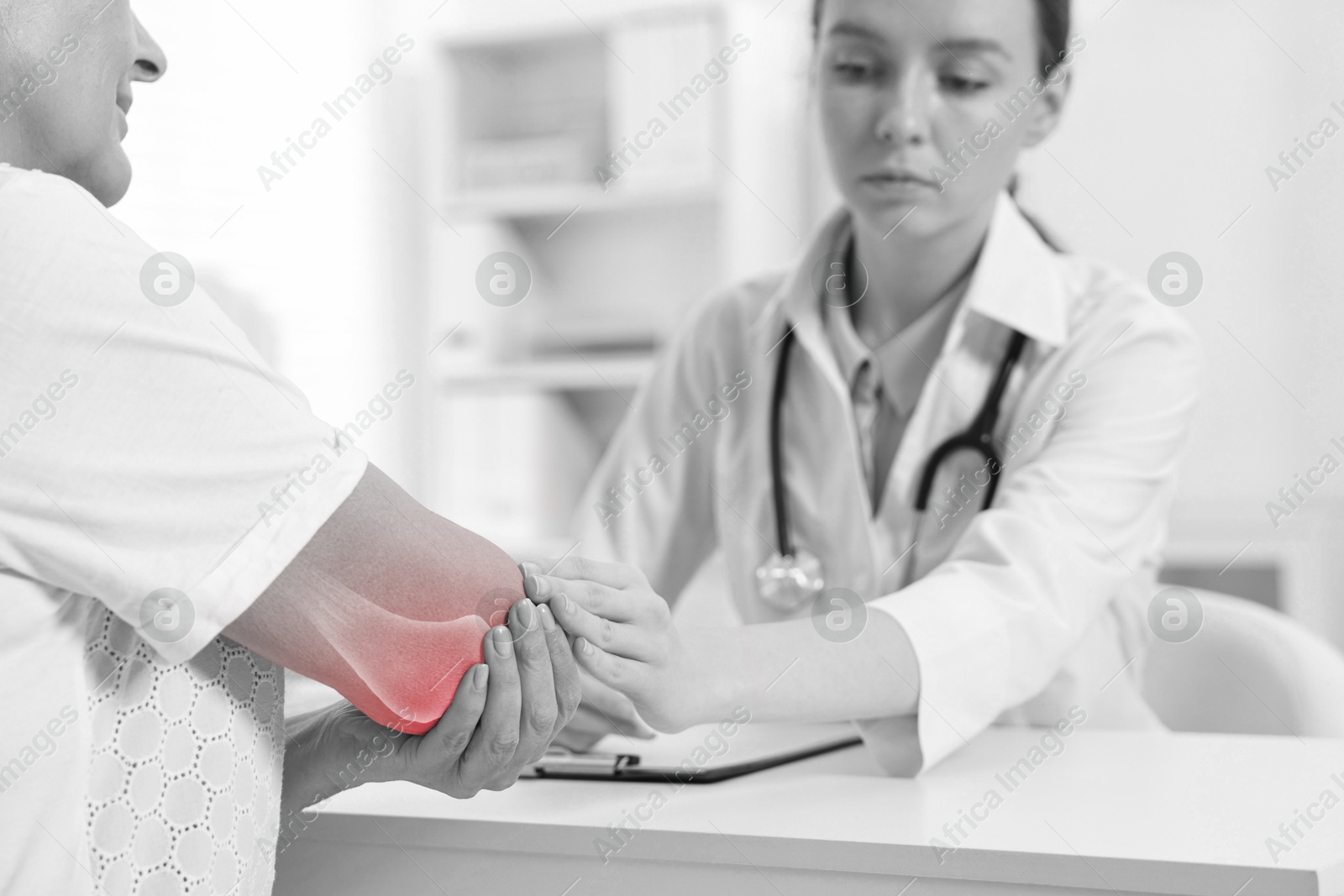 Arthritis. Doctor examining patient's elbow in hospital. Black and white toning with red color accent Image of Arthritis. Doctor examining patient's elbow in hospital. Black and white toning with red color accent