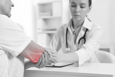 Image of Arthritis. Doctor examining patient's elbow in hospital. Black and white toning with red color accent