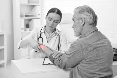 Image of Arthritis. Doctor examining patient's wrist in hospital. Black and white toning with red color accent