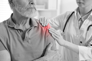 Image of Arthritis. Doctor examining patient with shoulder pain in hospital, closeup. Black and white toning with red color accent