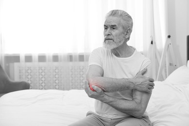 Image of Arthritis. Senior man suffering from pain in elbow at home. Black and white toning with red color accent