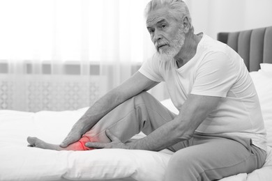 Image of Arthritis. Senior man suffering from pain in leg at home. Black and white toning with red color accent