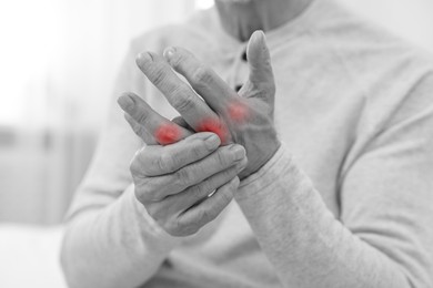 Image of Arthritis. Man suffering from pain in fingers indoors, closeup. Black and white toning with red color accent