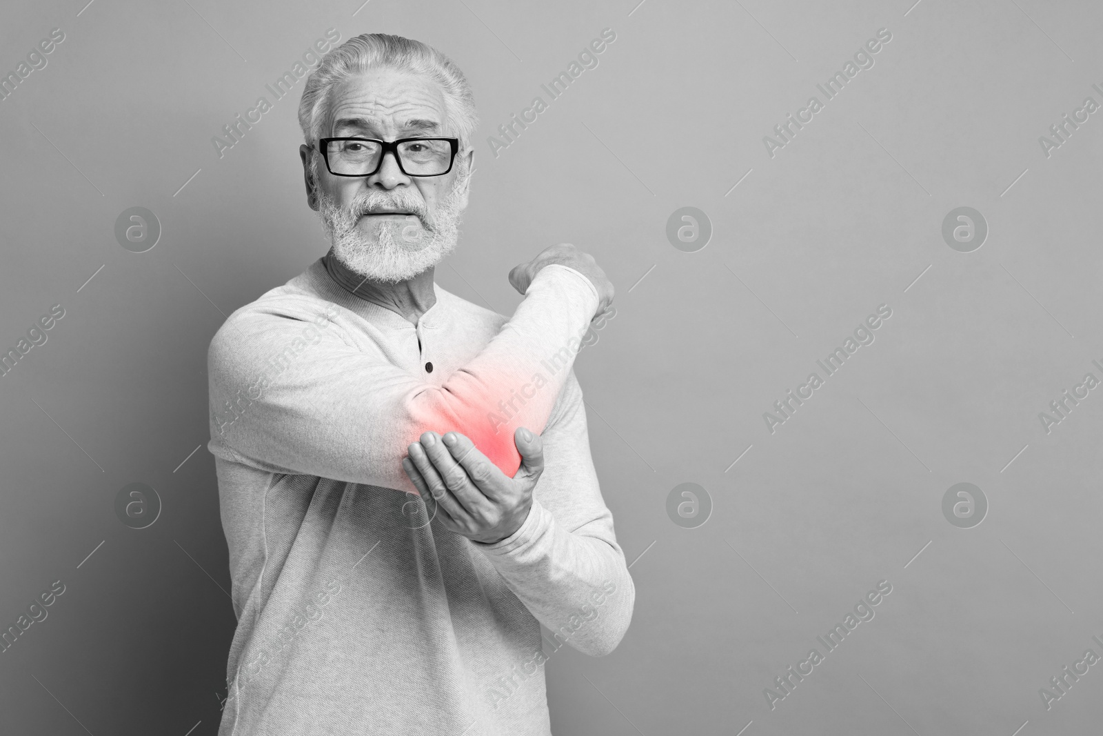 Arthritis. Senior man suffering from pain in elbow, space for text. Black and white toning with red color accent Image of Arthritis. Senior man suffering from pain in elbow, space for text. Black and white toning with red color accent