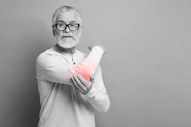 Image of Arthritis. Senior man suffering from pain in elbow, space for text. Black and white toning with red color accent