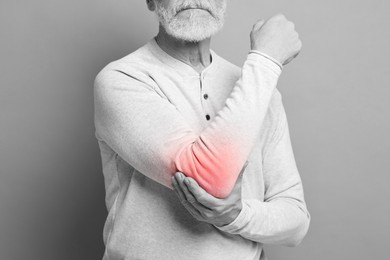 Image of Arthritis. Senior man suffering from pain in elbow, closeup. Black and white toning with red color accent