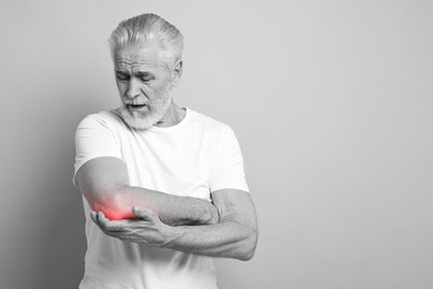 Image of Arthritis. Senior man suffering from pain in elbow, space for text. Black and white toning with red color accent