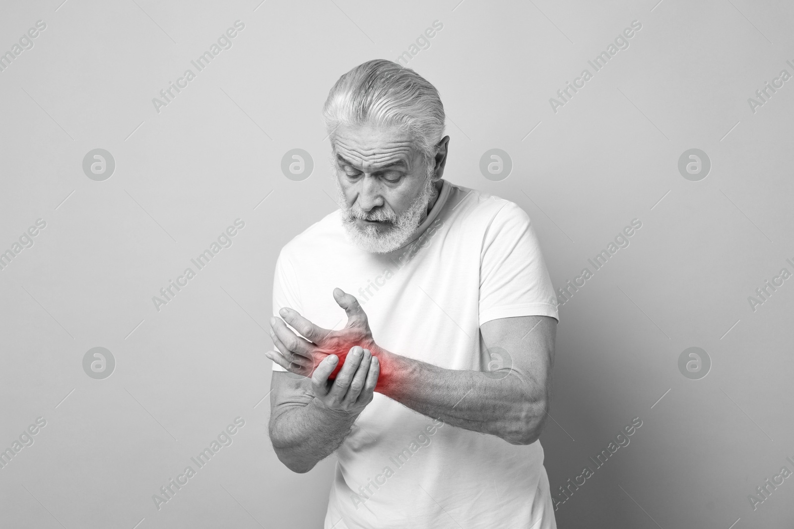 Arthritis. Senior man suffering from pain in wrist. Black and white toning with red color accent Image of Arthritis. Senior man suffering from pain in wrist. Black and white toning with red color accent