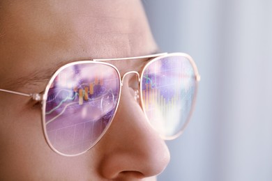 Image of Stock exchange. Trader analyzing data, closeup. Graphs reflecting in his eyeglasses