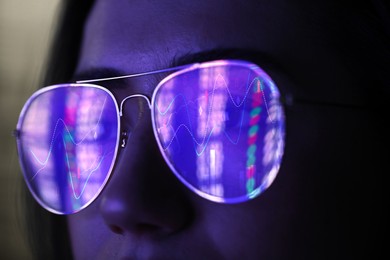 Image of Stock exchange. Trader analyzing data, closeup. Graphs reflecting in her eyeglasses