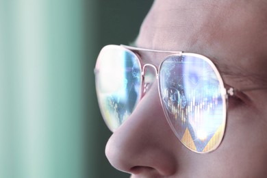 Image of Stock exchange. Trader analyzing data, closeup. Graphs reflecting in his eyeglasses