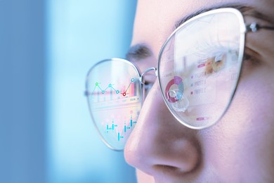 Image of Stock exchange. Trader analyzing data, closeup. Graphs and information reflecting in her eyeglasses