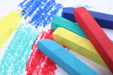 Photo of Colorful pastel chalks on white background, closeup. Drawing materials