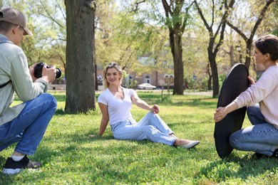 Photo of Professional photographers with reflector and camera near model during shooting outdoors on sunny day