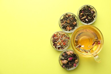 Photo of Delicious herbal tea in glass cup and dry leaves on green background, flat lay. Space for text