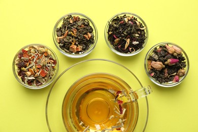 Photo of Delicious herbal tea in glass cup and dry leaves on green background, flat lay