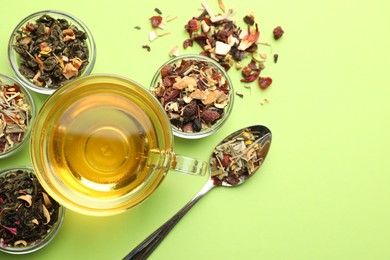 Photo of Delicious herbal tea in glass cup and dry leaves on light green background, flat lay