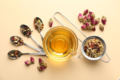 Photo of Delicious herbal tea in glass cup and dry leaves on beige background, flat lay