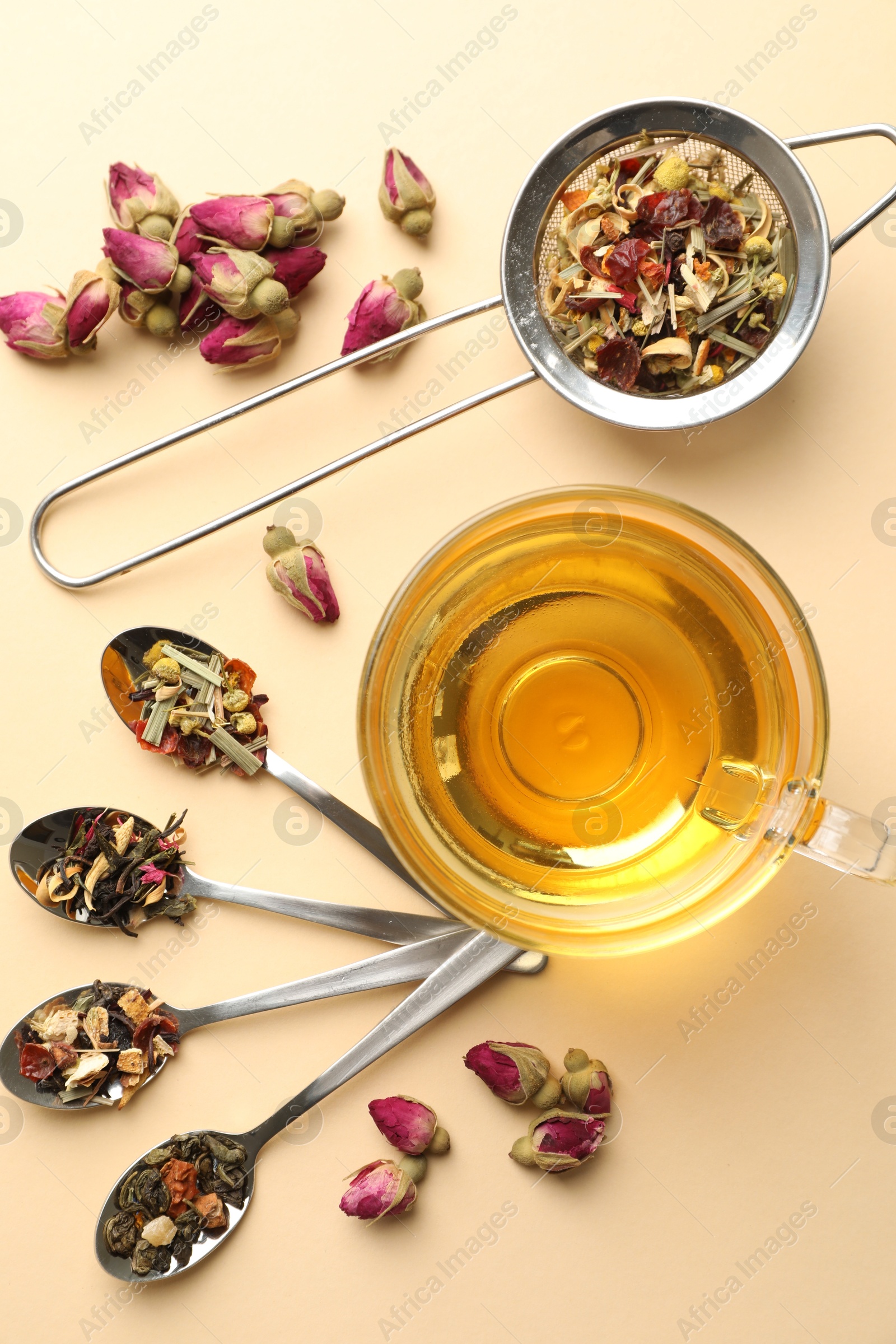Delicious herbal tea in glass cup and dry leaves on beige background, flat lay Photo of Delicious herbal tea in glass cup and dry leaves on beige background, flat lay