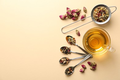 Photo of Delicious herbal tea in glass cup and dry leaves on beige background, flat lay. Space for text