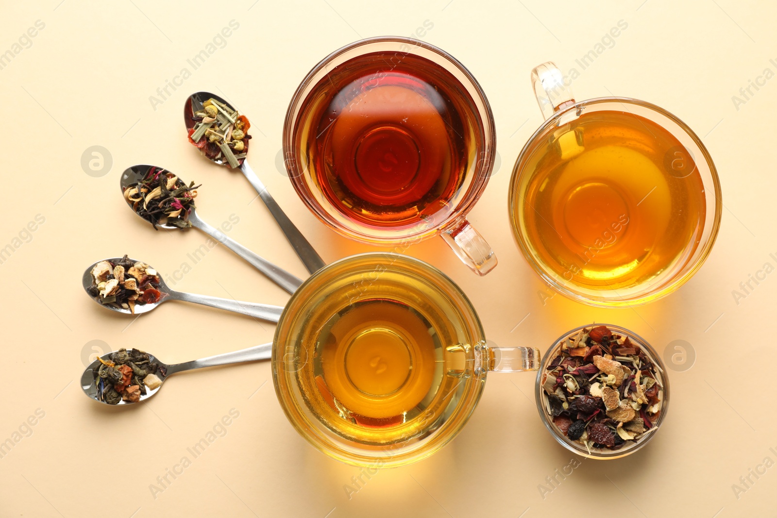Different freshly brewed teas and dry leaves on beige background, flat lay Photo of Different freshly brewed teas and dry leaves on beige background, flat lay