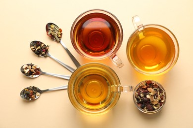 Photo of Different freshly brewed teas and dry leaves on beige background, flat lay