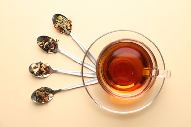 Photo of Delicious herbal tea in glass cup and dry leaves on beige background, flat lay